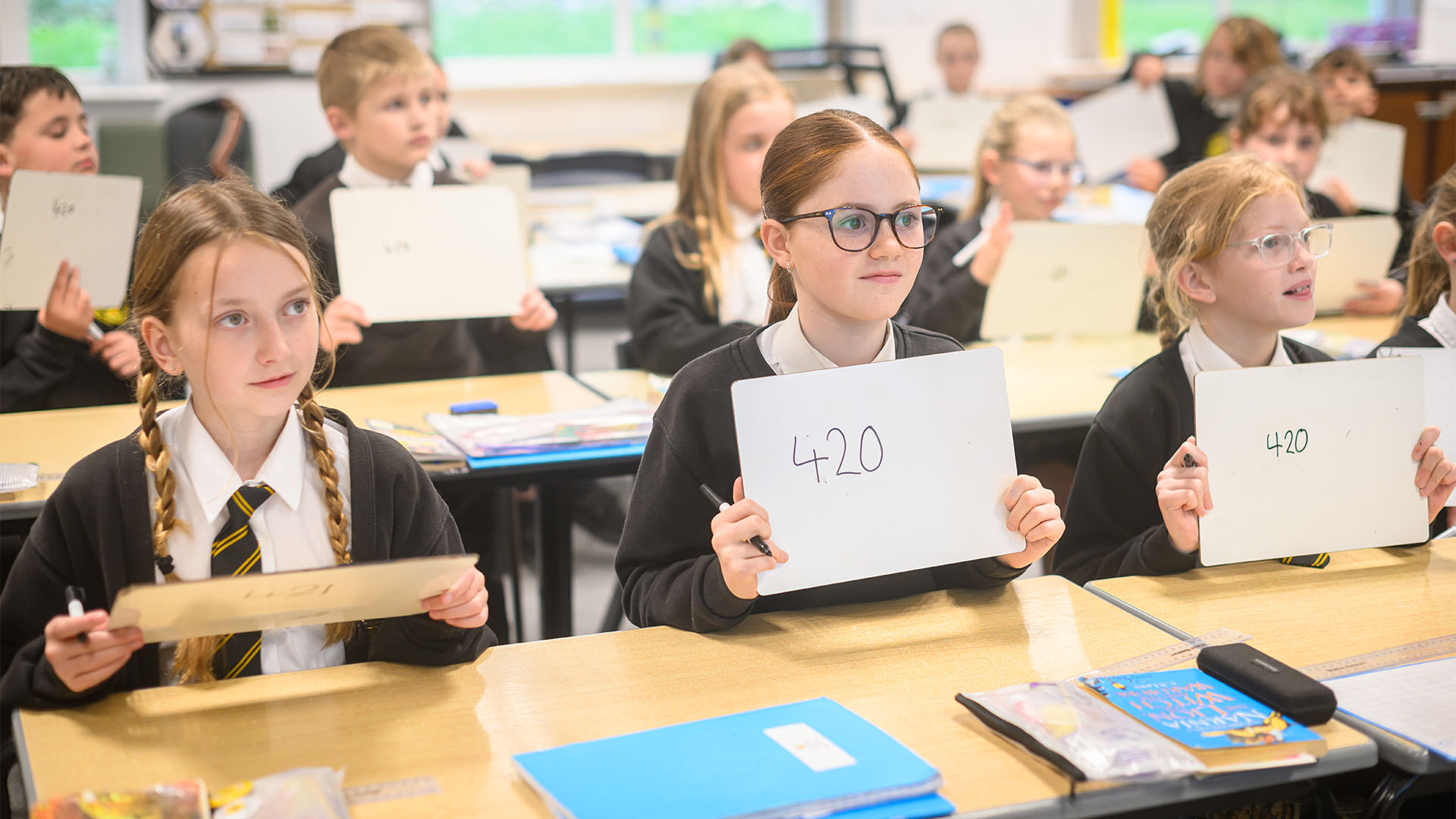 Three pupils holding up mini whiteboards